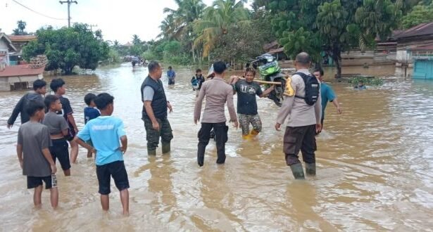 Anggota Polsek Batang Cenaku beserta warga sekitar membantu menyeberangkan kendaraan yang melintas.